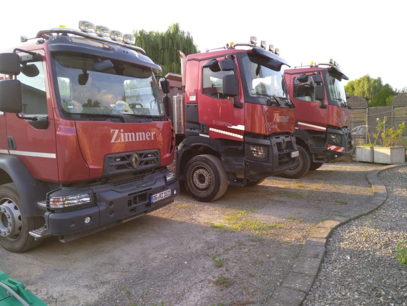 LKW-Fuhrpark Drei rote Lkw parken nebeneinander auf einem Hof.