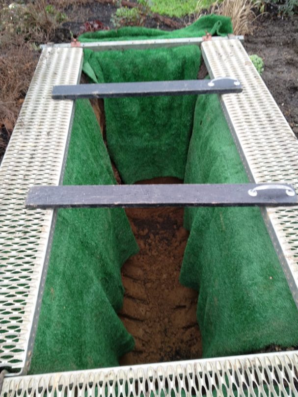 Vorbereitetes Grab Offenes Grab mit grünem Samt ausgeschlagen und Holzabdeckungen.